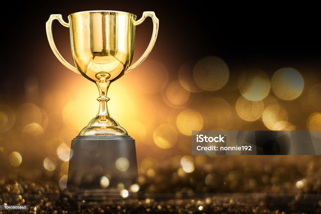 trophy over wooden table and dark background Trophy - Award Stock Photo