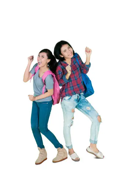 Full length of two female college students looks happy while dancing together in the studio