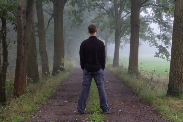 istock Young man standing on path in morning misty fog from back 1040834566