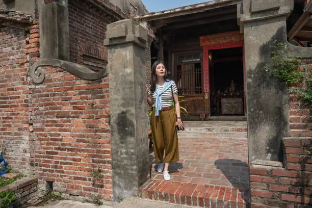 standing in the old tranditional house. asian woman visiting one of the oldest house.