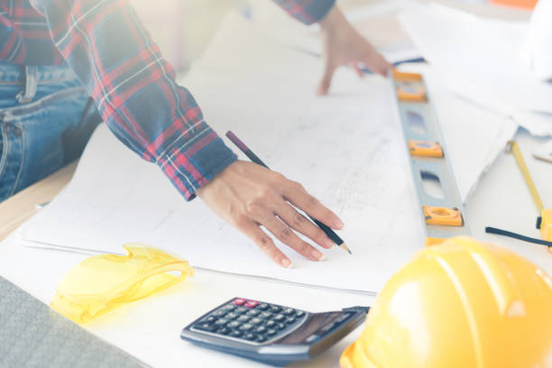 istock Hands of female architect or engineer using pencil working with blueprint on desk in office. 1040845924