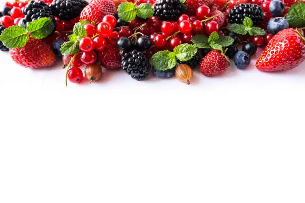 Mix berries on a white background. Ripe red currants, strawberries, blackberries, blueberries, blackcurrants, gooseberries with mint leaves on white background. Top view. Fruits with copy space for text. Black-blue and red food.