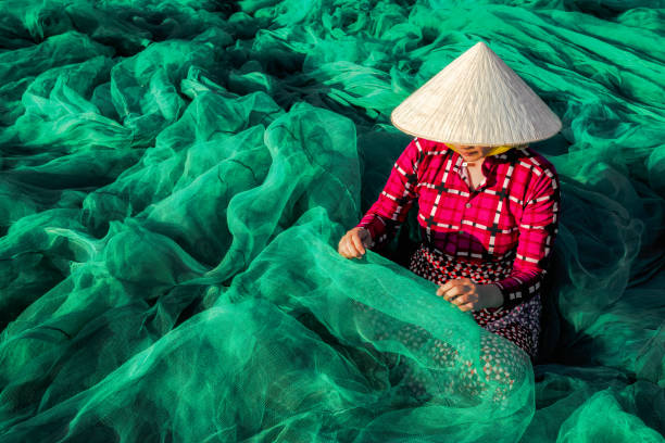 mujer vietnamita sentado reparar la red de los pescados. - thread needle sewing red fotografías e imágenes de stock