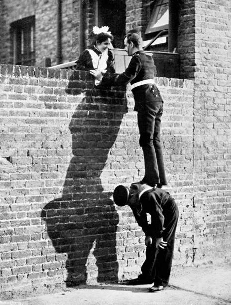 victorian imagem de um soldado que ficou no topo de um marinheiros volta para que ele pode falar com uma moça bonita em cima de um muro alto; humor do século xix; da marinha e do exército ilustrado 1899 - divertimento fotos - fotografias e filmes do acervo