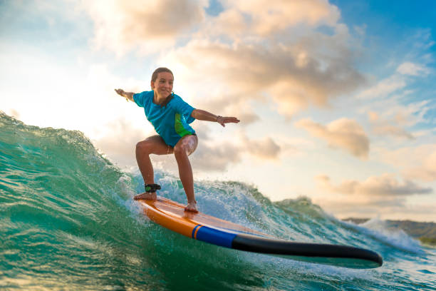 junges mädchen surfen bei sonnenuntergang - surf stock-fotos und bilder