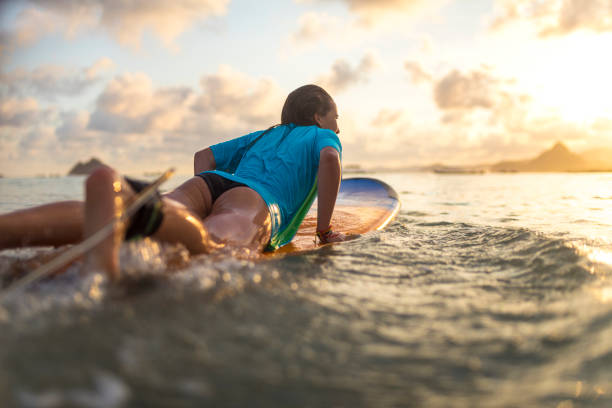 istock Young girl surfing at sunset 1040907142