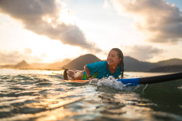 Young girl surfing at sunset