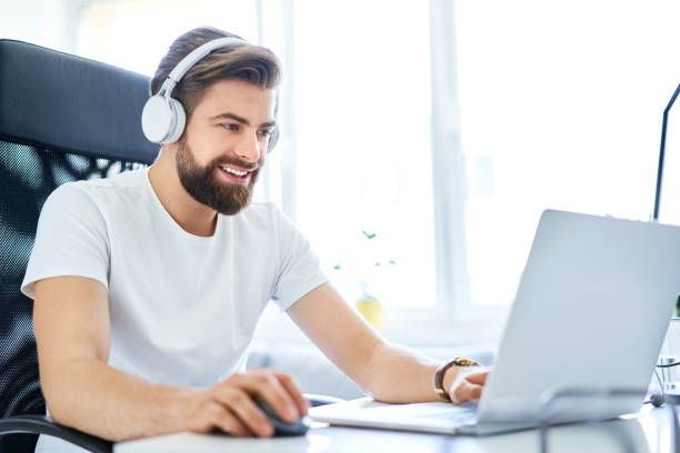 istock Man working on laptop with headphones from home office. Student working on laptop from dorm room 1040911372
