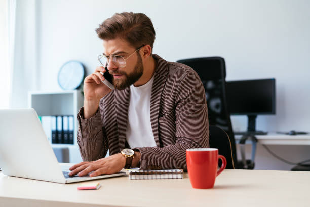 istock Young businessman talking on phone while working with laptop in home office 1040912450