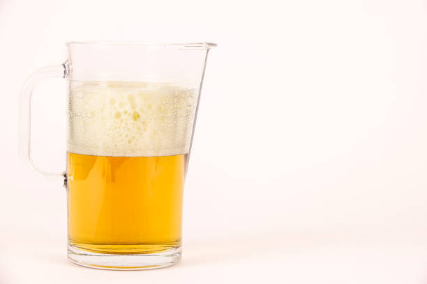 Pitcher of beer with foam on white background with empty copy space for text.