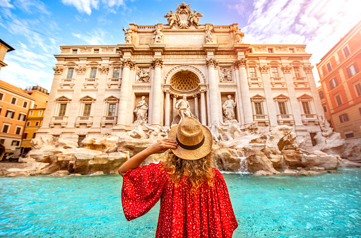 Beautiful woman in front of famous iconic Trevi Fountain at Rome, Italy.