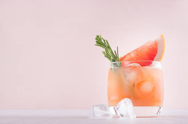 istock Cold grapefruit alcohol cocktail in misted glass with rosemary and grapefruits slice on pastel fashion pink background. 1040921050