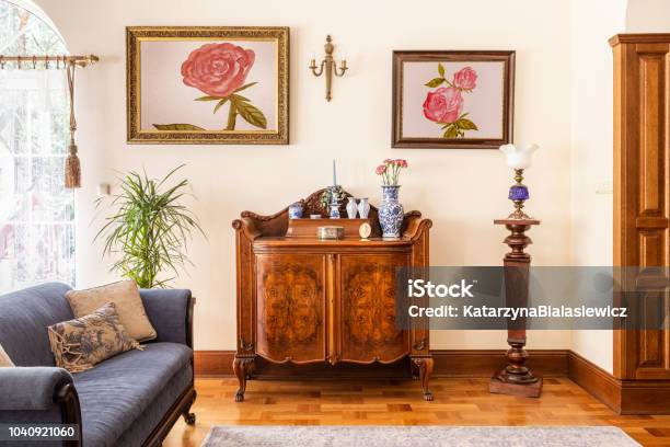 Real Photo Of An Antique Cabinet With Porcelain Decorations Paintings With Roses And Blue Sofa In A Living Room Interior Stock Photo - Download Image Now