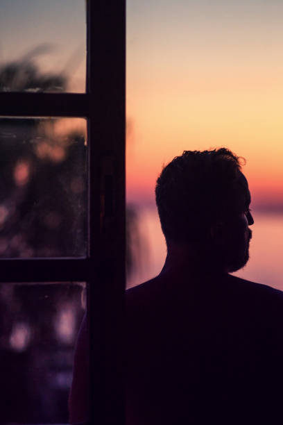 istock Man admires the sunset from window 1040921176