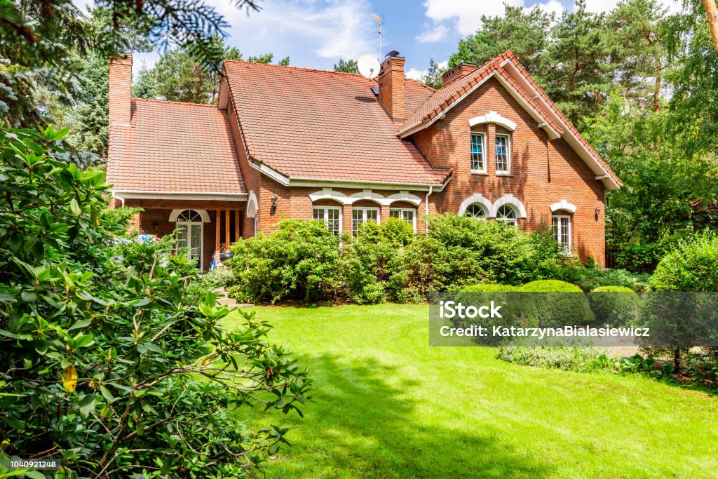 Backround yard of a beautiful english style house with bushes and green lawn. Real photo House Stock Photo