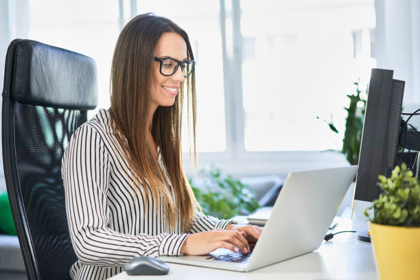 istock Smiling woman working on laptop in modern office 1040921544