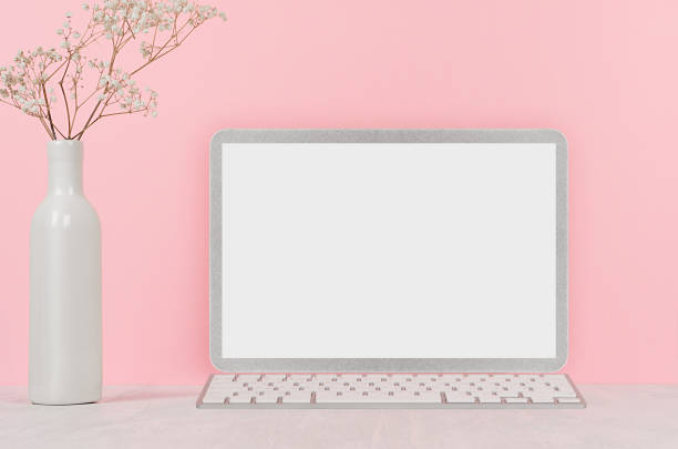 istock Elegant home workplace with stylish silver blank computer notebook and white flowers in vase on pink background. 1040921604