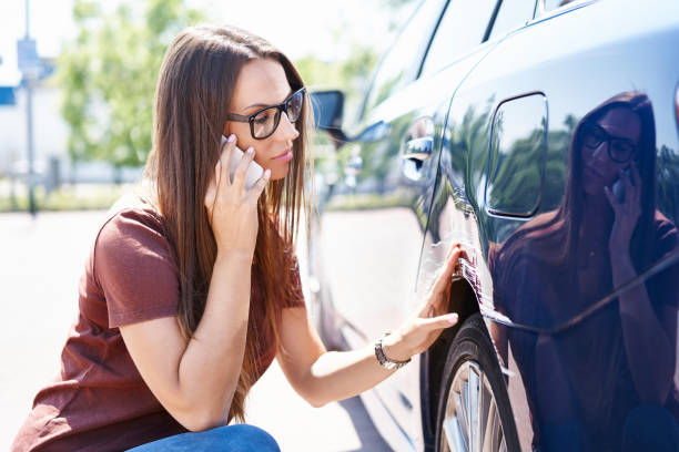 donna yougn che ispeziona la sua auto graffiata e chiama l'agente assicurativo - car insurance auto accidents accident foto e immagini stock