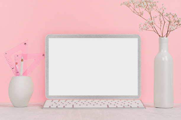 istock Elegant home workplace with stylish silver blank computer notebook and white stationery, flowers in vase on pink background. 1040926238