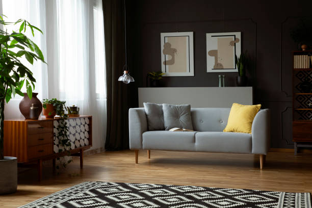 istock Dark living room interior in real photo with window with curtains, patterned carpet, retro cupboard and grey sofa with cushions 1040927924