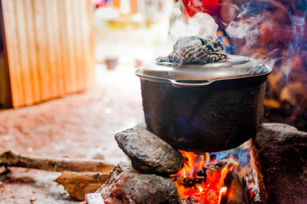 smoking iron pot above fire in traditional african kitchen in cameroon during cooking stock photo