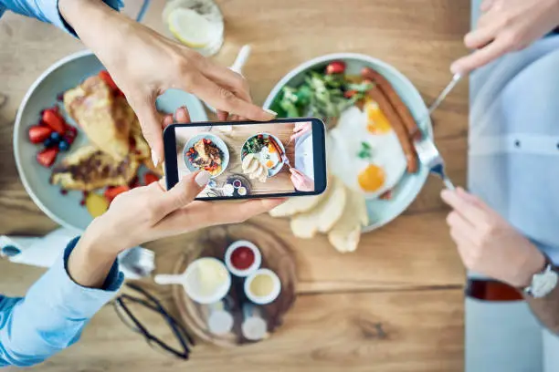 Woman taking photo of breakfast served in cafe. Couple having meal together