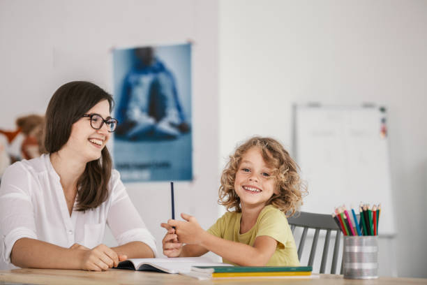 istock Smiling teacher and happy kid doing homework after classes 1040930850