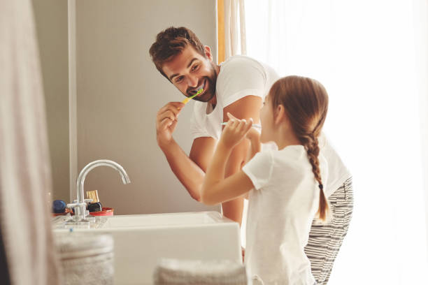 Don't you want a smile like this? Cropped shot of a handsome young man and his little daughter brushing their teeth in the bathroom lens flare offspring daughter human age stock pictures, royalty-free photos & images