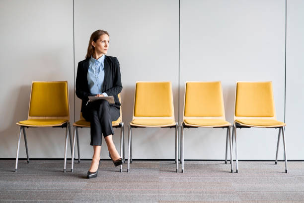молодая женщина сидит в вестибюле с резюме в руках и ждет собеседования - recruitment interview job interview job search стоковые фото и изображения