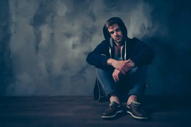 Photo of Loneliness helpless adolescence people concept. Full size length body photo of bearded tired exhausted man thinking pondering about life sitting in corner