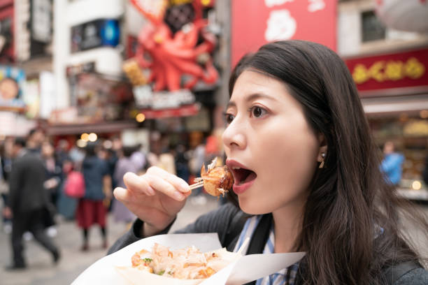 istock beautiful asian female eating takoyaki. view from side 1040939308