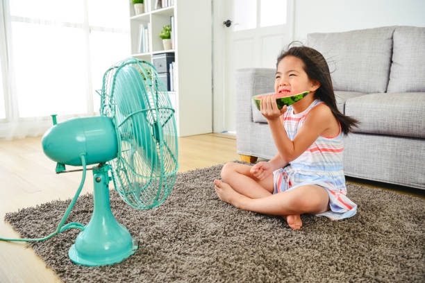 istock kid feeling cold while sitting in front of fan. 1040941130