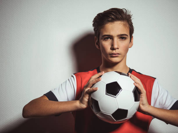 foto di ragazzo adolescente in abbigliamento sportivo che tiene palla da calcio - teenage boys teenager teenagers only adolescence foto e immagini stock