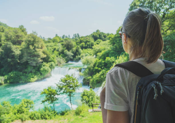 istock Female tourist with backpack looking at waterfalls. 1040945216