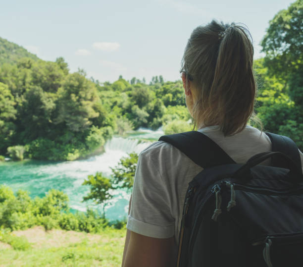 istock Female tourist with backpack looking at waterfalls. 1040945228