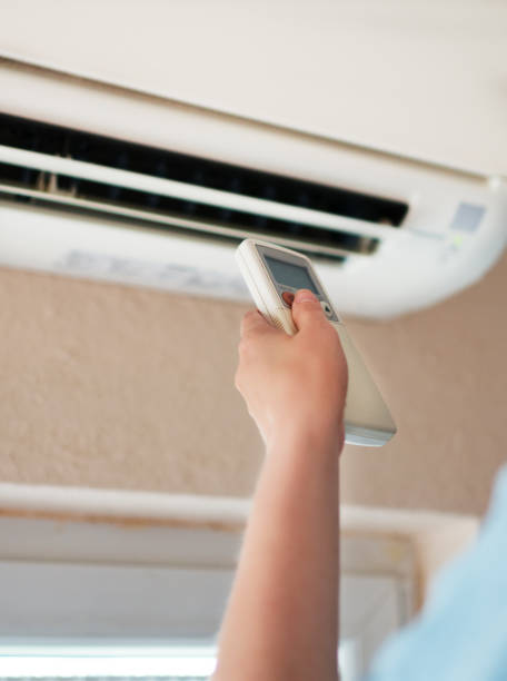 istock Hand holding remote control aimed at the air conditioner. 1040945412