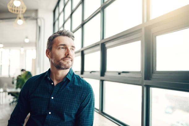 You can wait for opportunity or you can create it Shot of a mature businessman looking thoughtfully out of an office window business man looking away stock pictures, royalty-free photos & images