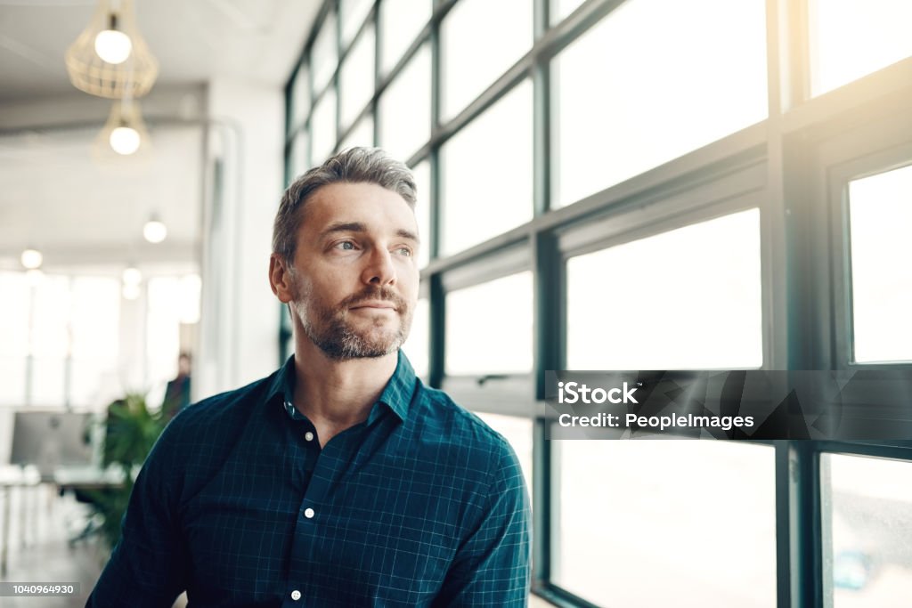 Opportunity doesn’t hang around, neither should you Shot of a mature businessman looking thoughtfully out of an office window Men Stock Photo