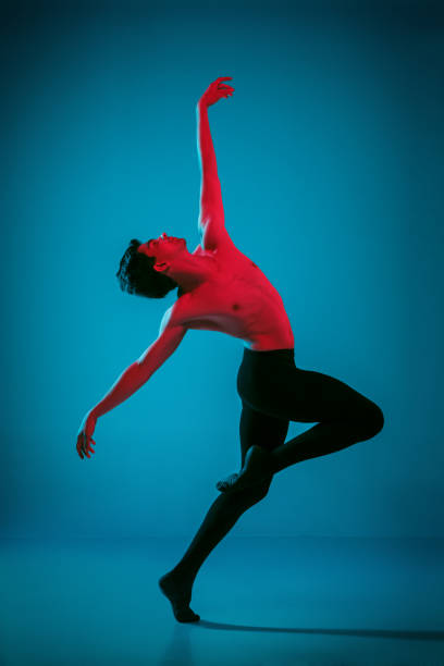 istock The male athletic ballet dancer performing dance on blue background. Studio shot. Ballet concept. Fit young man. Caucasian model 1040965370