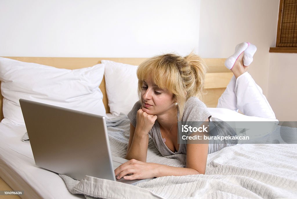 Businesswoman lying on bed and using a laptop  30-39 Years Stock Photo