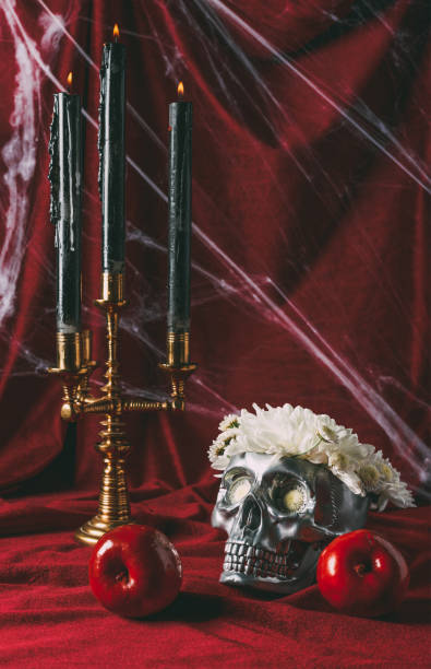 istock apples, silver skull with flowers and candelabrum with candles on red cloth with spider web 1040969444