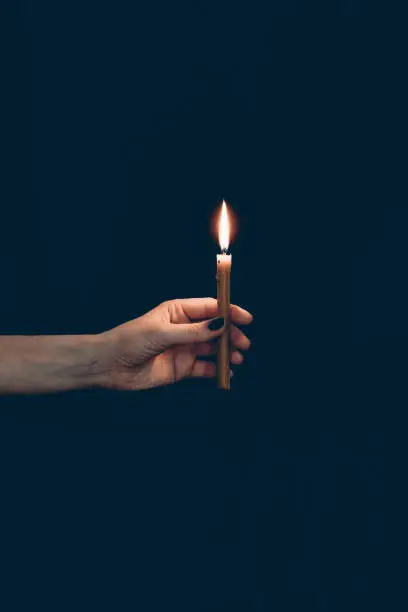 Photo of partial view of girl holding flaming candle isolated on black