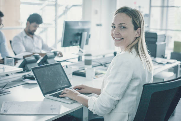 istock Woman using laptop and looking at camera. Colleagues working together. 1040974298