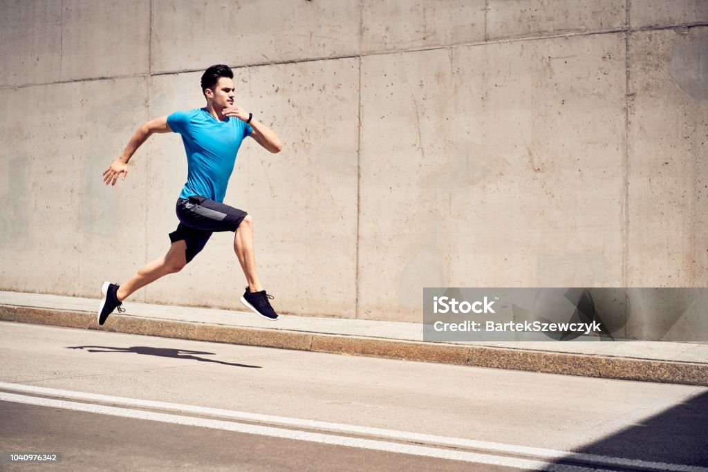 Health and fitness concept. Man doing sprinting and jumping exercises during workout session in the city Men Stock Photo