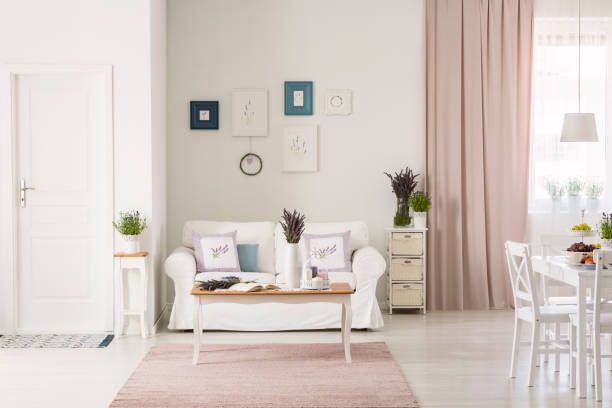 istock Lavender flowers on table in front of white couch in flat interior with pink drapes and posters. Real photo 1040980124