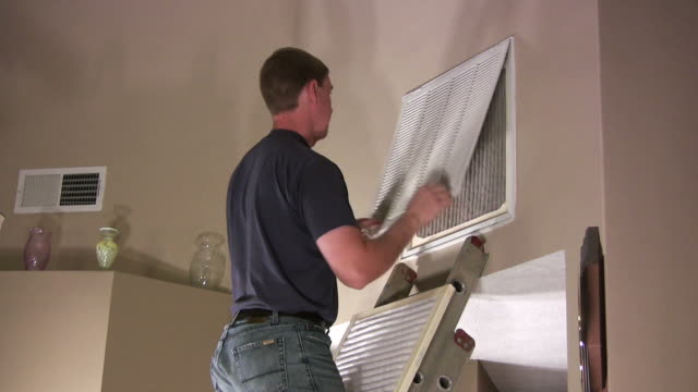 A video of a young man changing the air filter in his house.