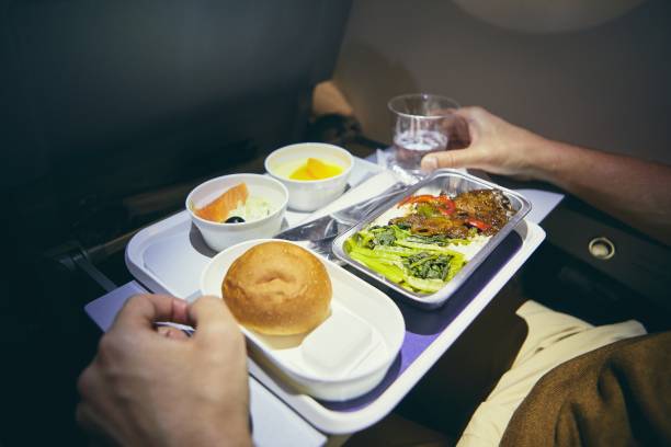 Dinner in economy class Traveling by airplane. Passenger enjoying dinner in economy class during long haul flight. economy class stock pictures, royalty-free photos & images