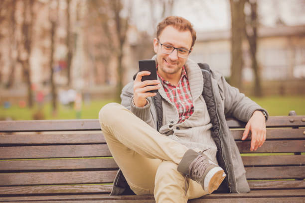 istock Attractive man sitting on the bench and using cellphone  outdoors. 1040989812