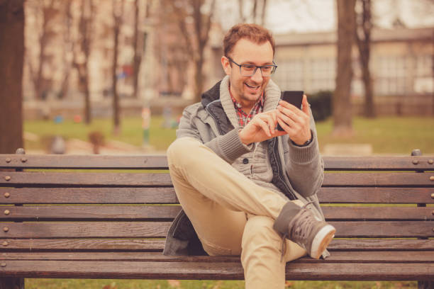 istock Attractive man sitting on the bench and using cellphone  outdoors. 1040990720