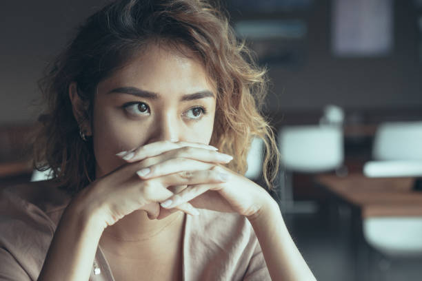 istock Serious Woman Covering Mouth with Clasped Hands 1040991420
